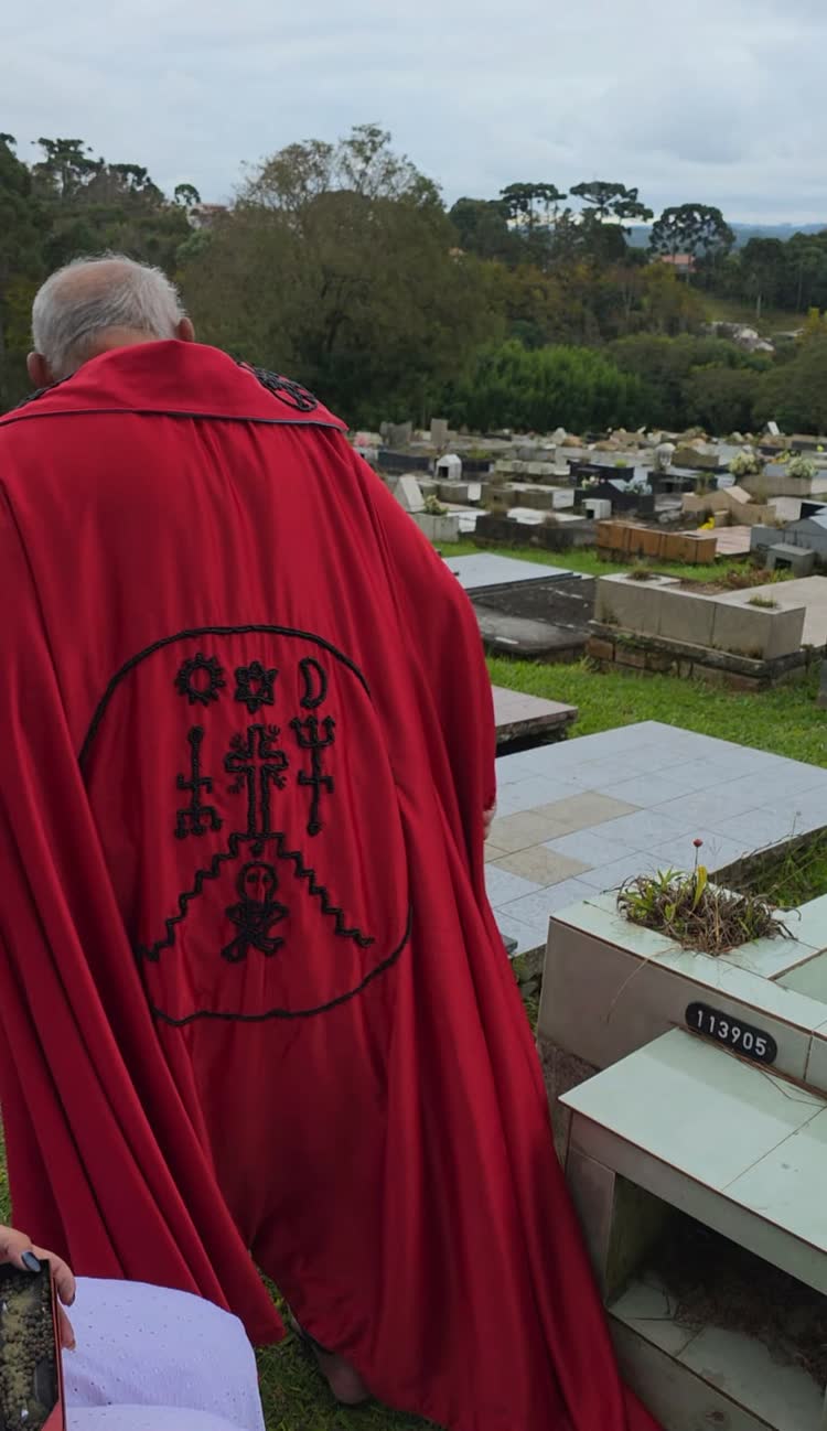 Pai Cláudio de costas com a capa vermelha bordada com o símbolo da casa